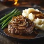 A juicy chopped steak covered in brown onion gravy with mashed potatoes.